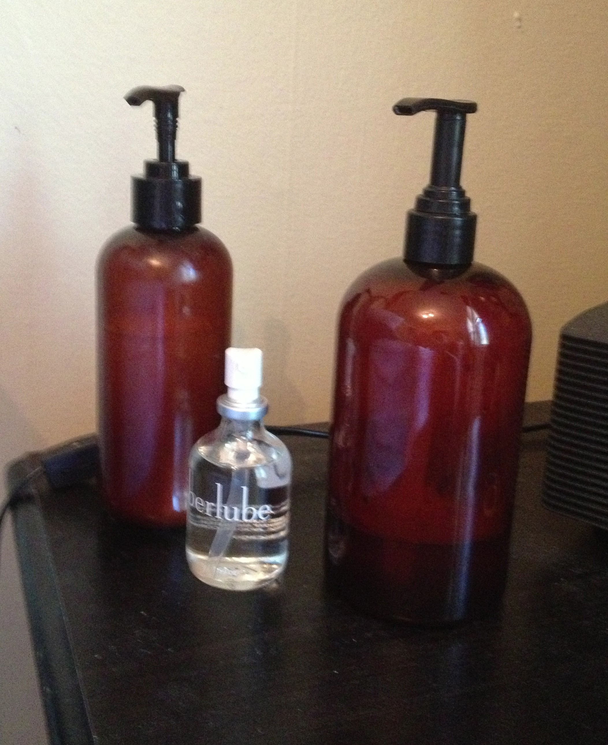 Two brown plastic pump bottles and one small clear uberlube pump bottle