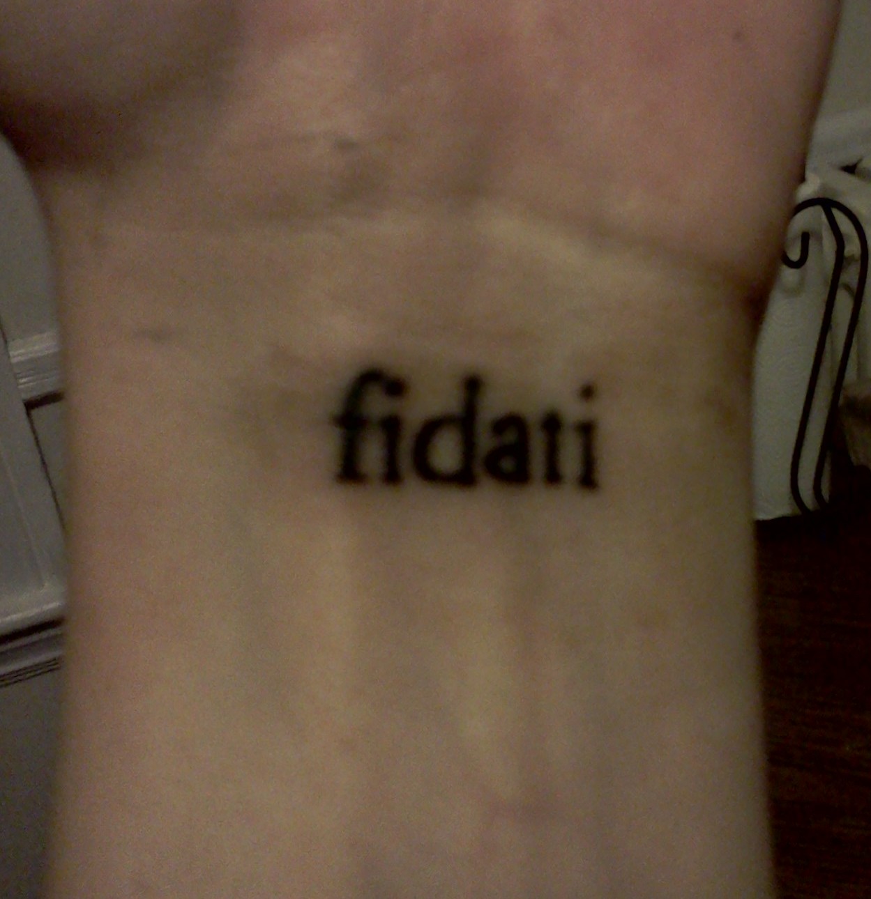 An inner wrist with a tattoo reading "fidati"