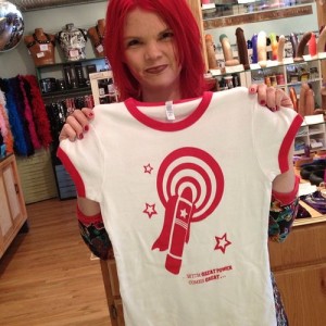 JoEllen holding a white t-shirt with red rings around the neck and sleeves and a red vibrator design