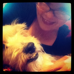 JoEllen wearing brown glasses and posing with a small beige dog with an underbite