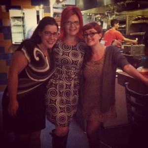 Three women - one brunette and two redheads- standing together in a restaurant.
