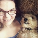 JoEllen wearing glasses and smiling with small beige dog whose visible underbite makes him look like he's smiling too