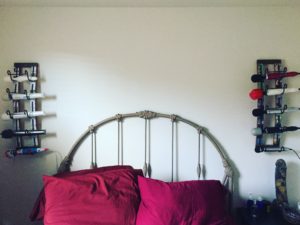 A bed flanked by two wine racks. Each rack holds 5 wand vibrators.
