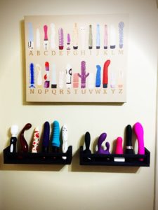 painting depicting multiple sex toys hanging over shelves of sex toys