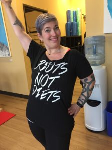 Woman with short hair showing off a shirt that reads "Riots not diets"