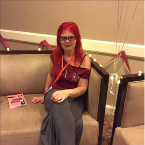 JoEllen sitting on a couch in sweatpants and a Doxy t-shirt